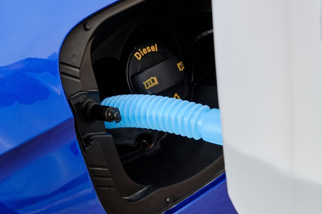 Close up filling of diesel exhaust fluid from canister into the tank of blue car for reduction of